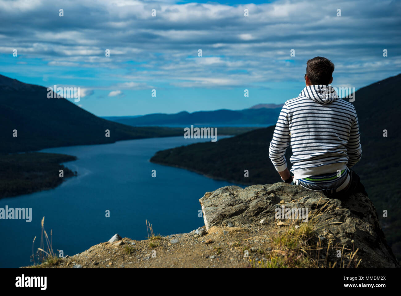 Ragazzo seduto sulla battuta di una rupe Foto Stock