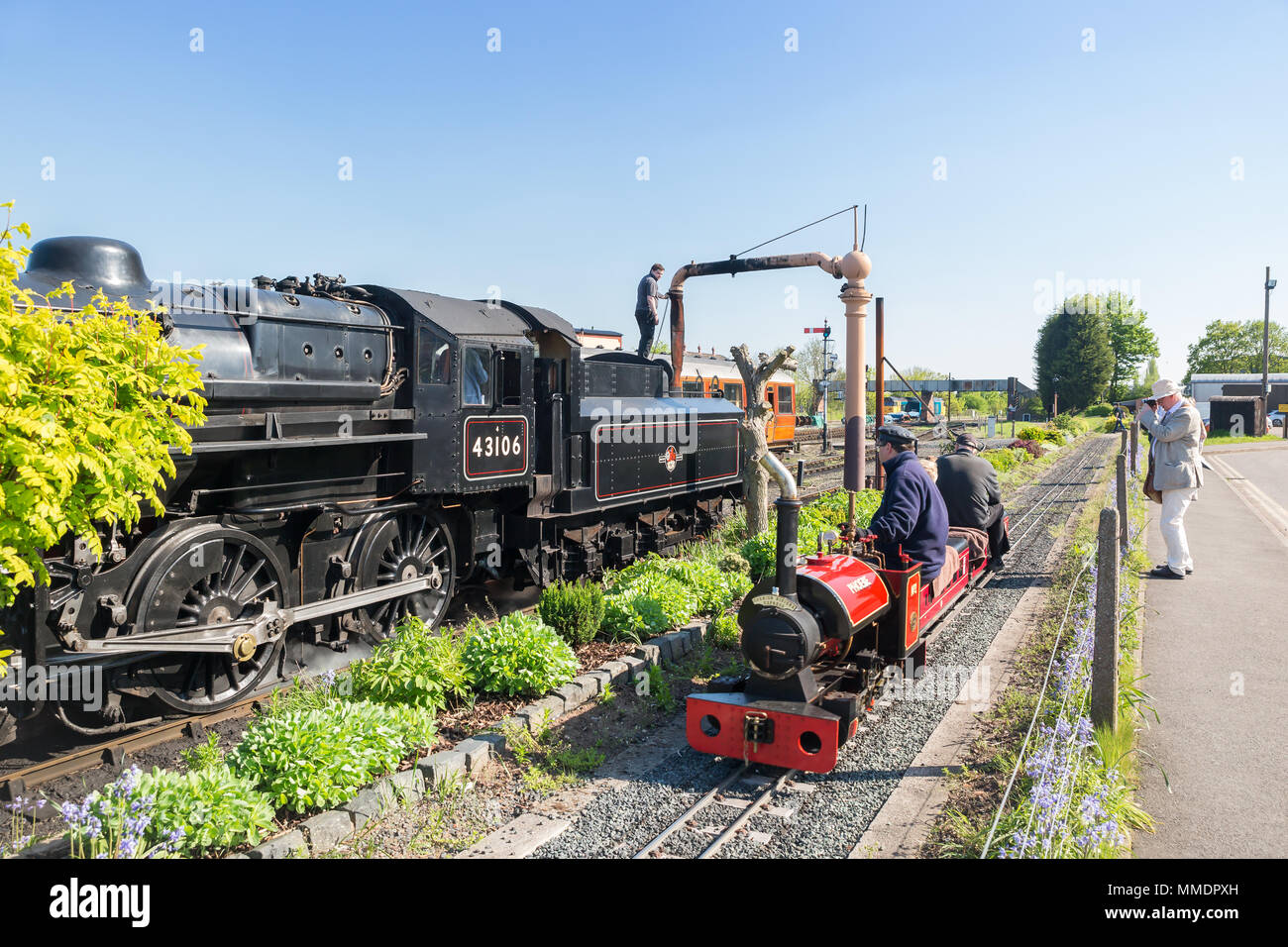 Piccoli e grandi concept al patrimonio del Regno Unito ferrovia. Vintage UK locomotiva a vapore impiega acqua sul fianco a fianco con i bambini della ferrovia in miniatura ride. Foto Stock