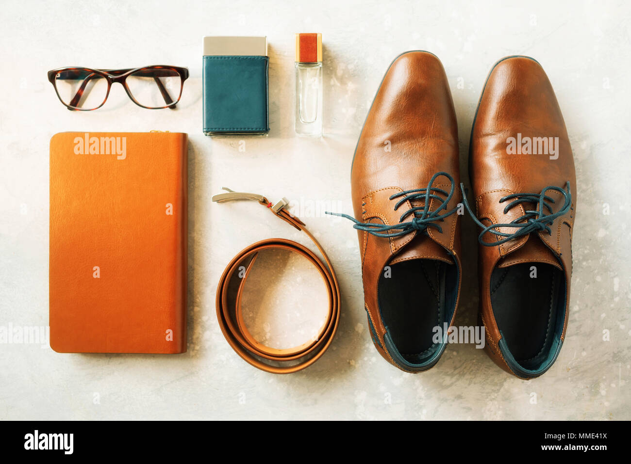 Uomo accessori e scarpe su sfondo grigio. Piatto di laici elegante cinghia, occhiali, profumi, notebook. Set Elegante e concetto di moda per uomo Foto Stock