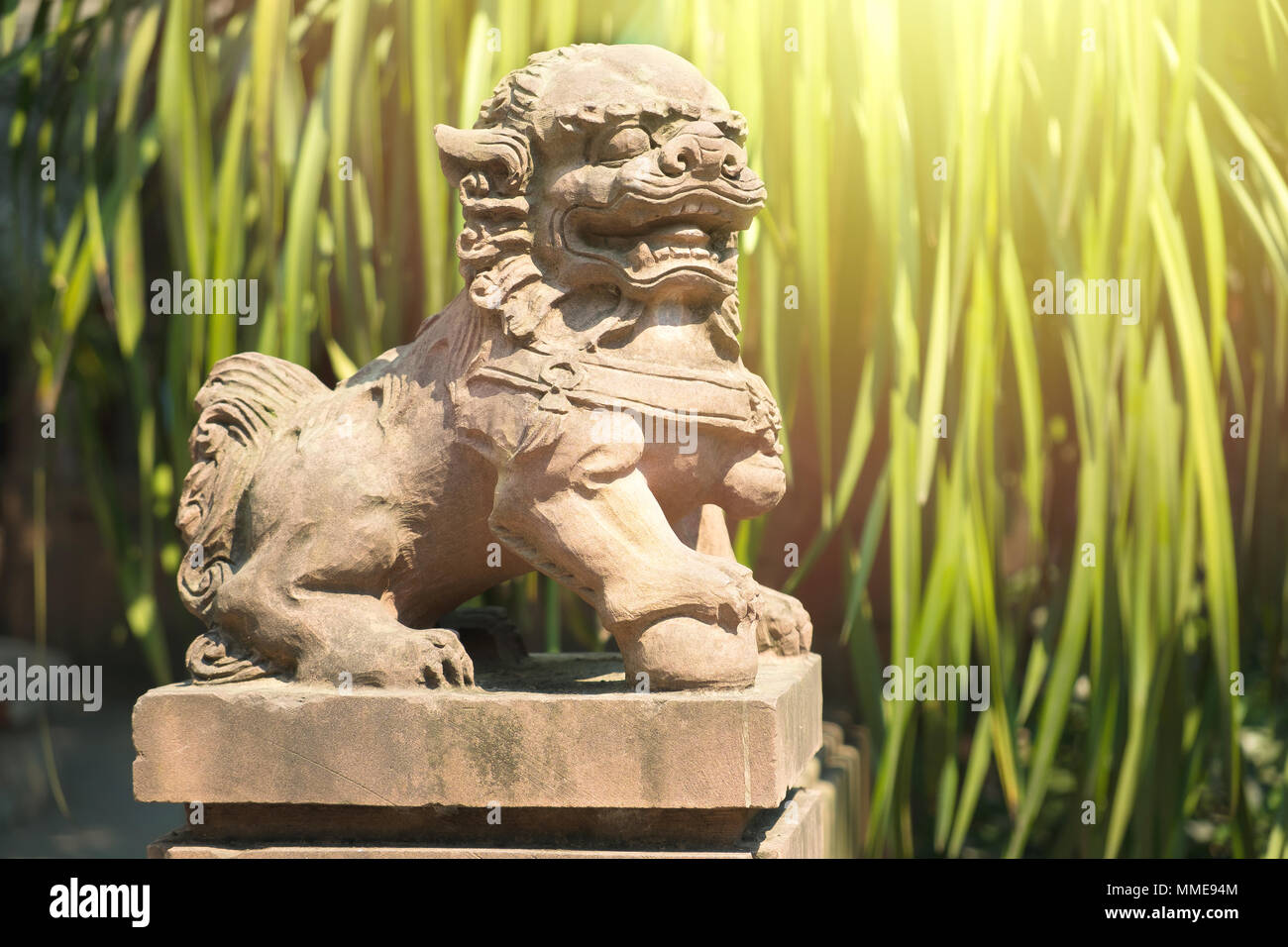Leone cinese statua in un tempio cinese con foglie verde backgroud Foto Stock