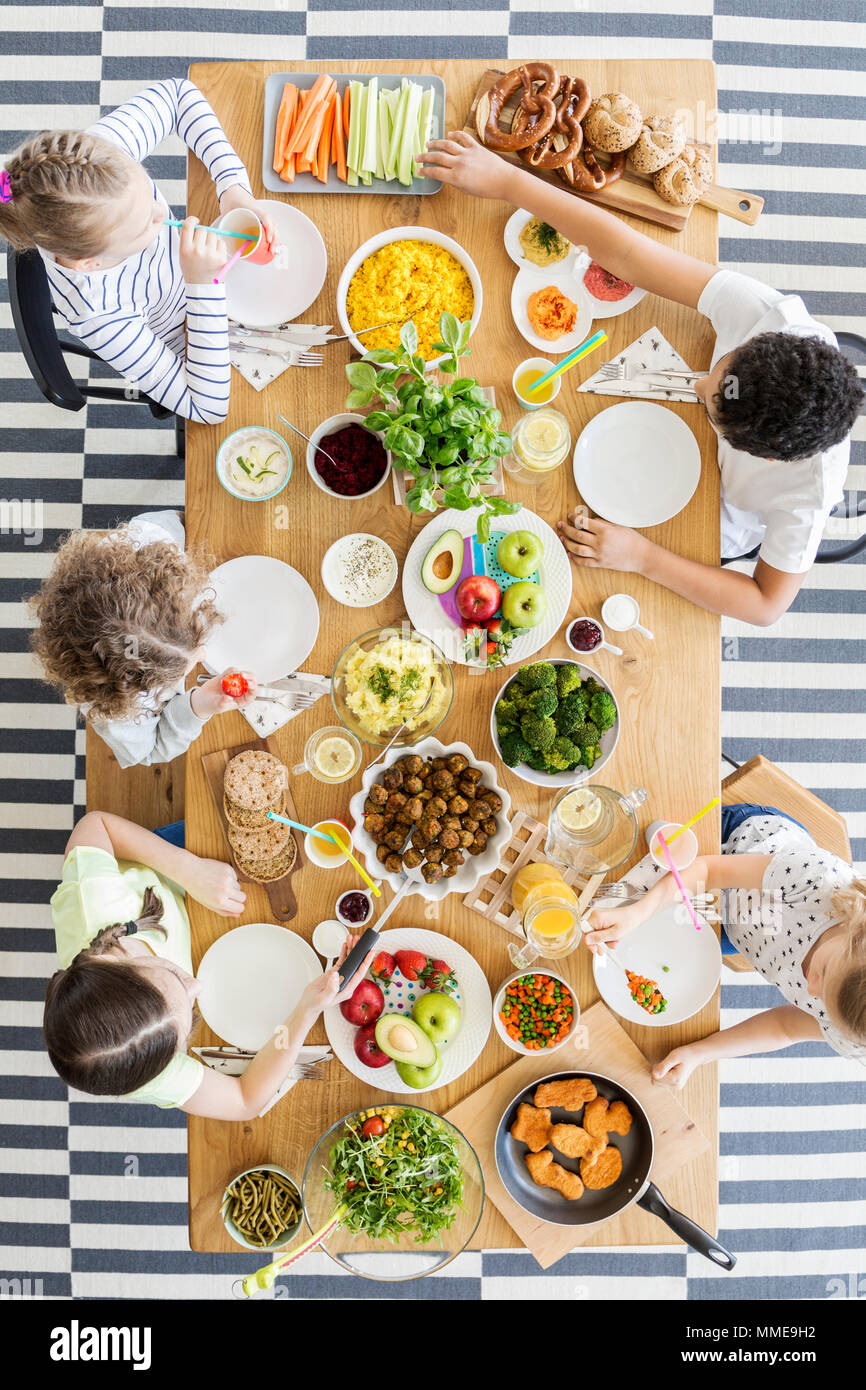 Vista dall'alto sui bambini a mangiare cibo sano a tavola durante la festa di compleanno Foto Stock