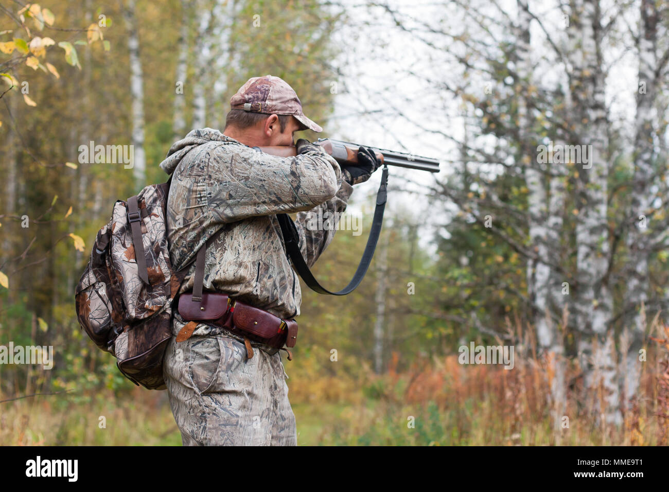 Hunter di camuffamento prendendo mirano da un fucile da caccia di quaglie Foto Stock