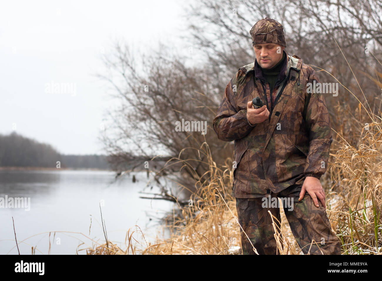 Uomo che guarda sul GPS Navigator sulla riva del fiume Foto Stock