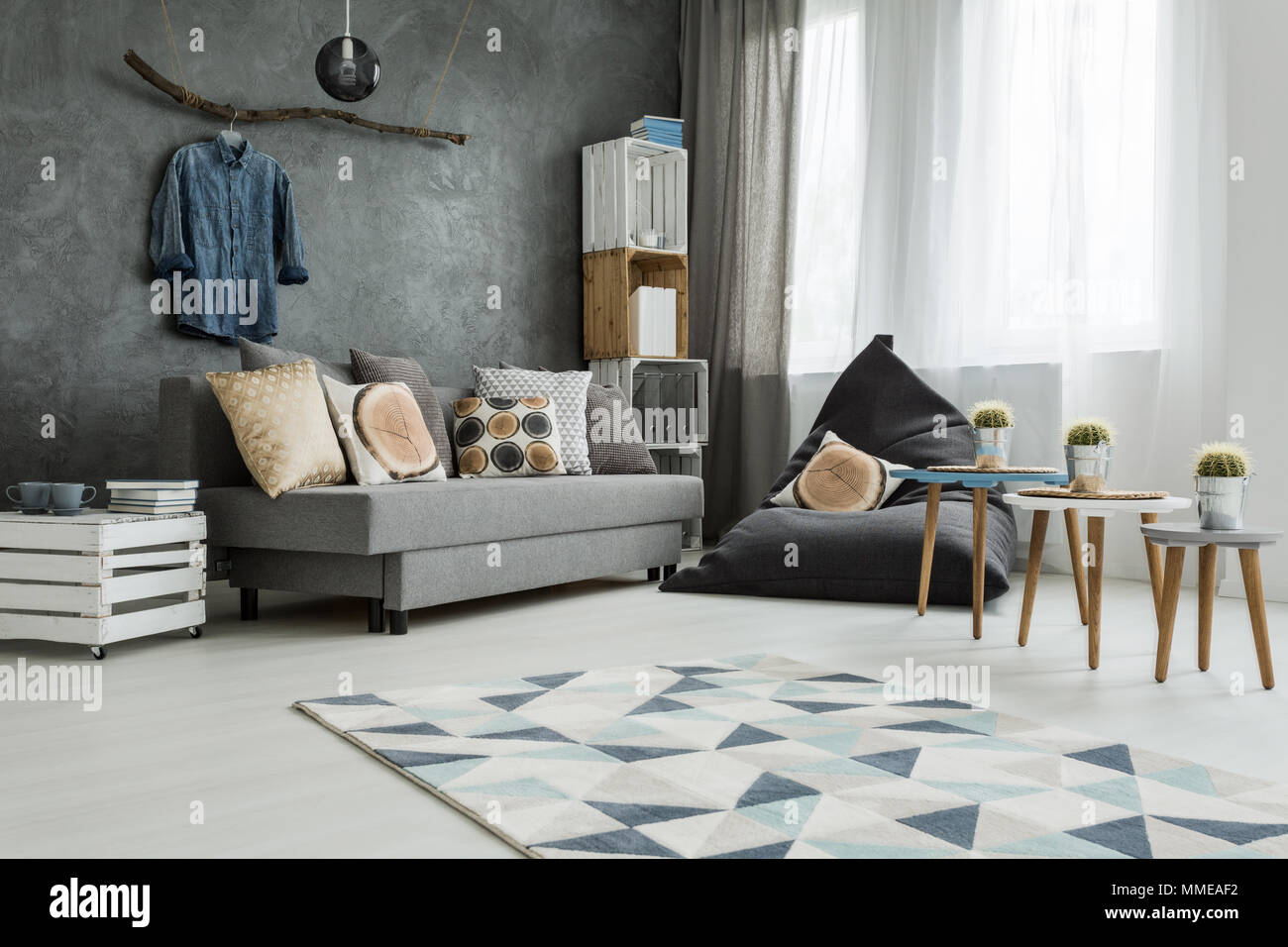 Nuovo appartamento interno in grigio con divano, pouf moderno, un piccolo  tavolo e due sedie e tappeti di pattern Foto stock - Alamy