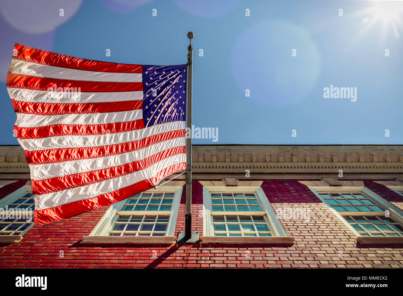 Una bandiera su un edificio di mattoni, con un paio di macchie solari, in Alexandria, Virginia. Foto Stock