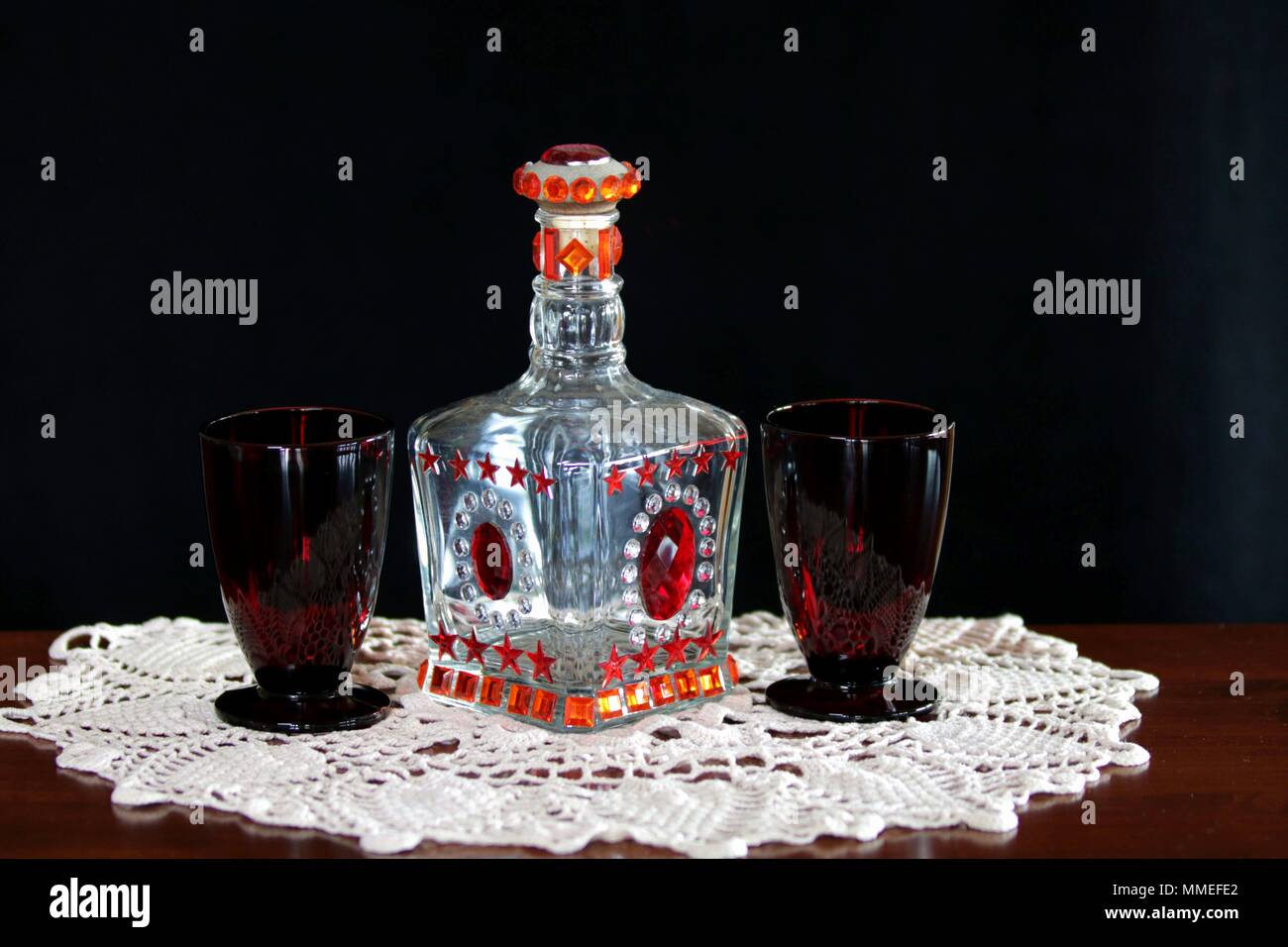 Vaso decorativo e rosso rubino occhiali antichi su un antico uncinetto centrino Foto Stock