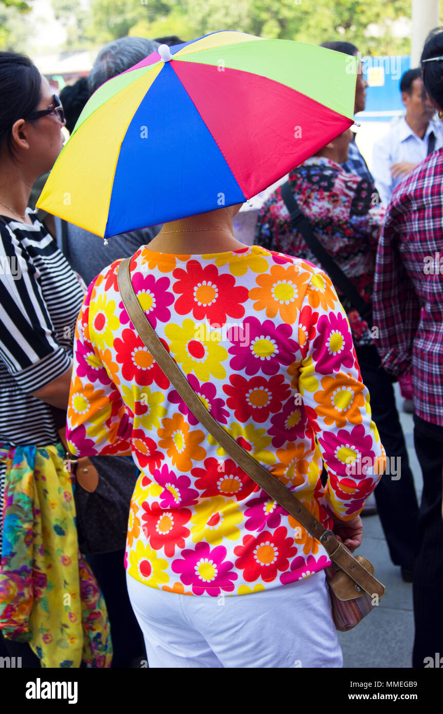 Una donna in piazza Tiananmen, Pechino, Cina, indossando un cappello conformata come un ombrello colorato. Foto Stock