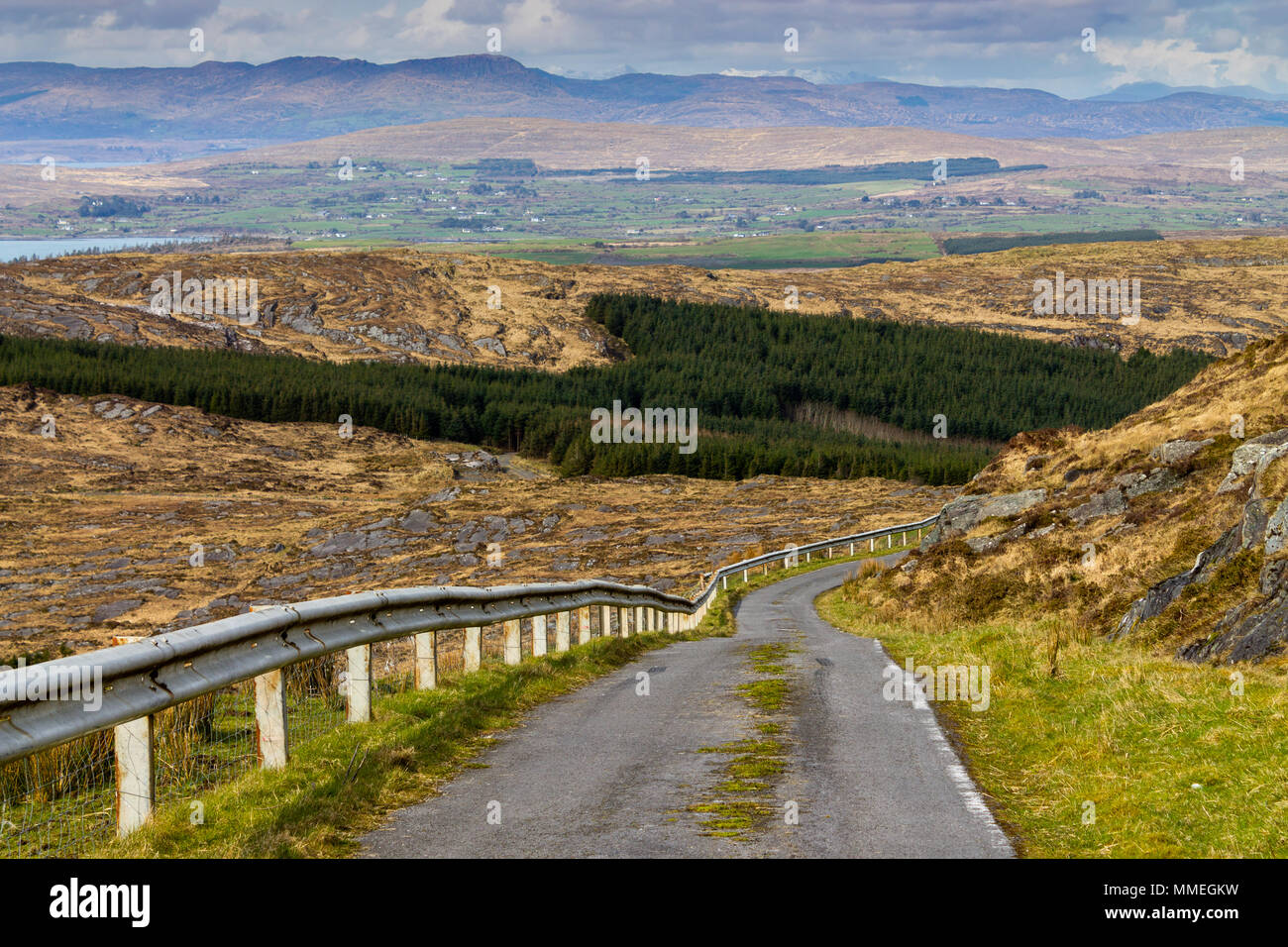 La strada che scende dal monte gabriel in Irlanda con vedute del paesaggio irlandese e cime innevate in lontananza. Foto Stock