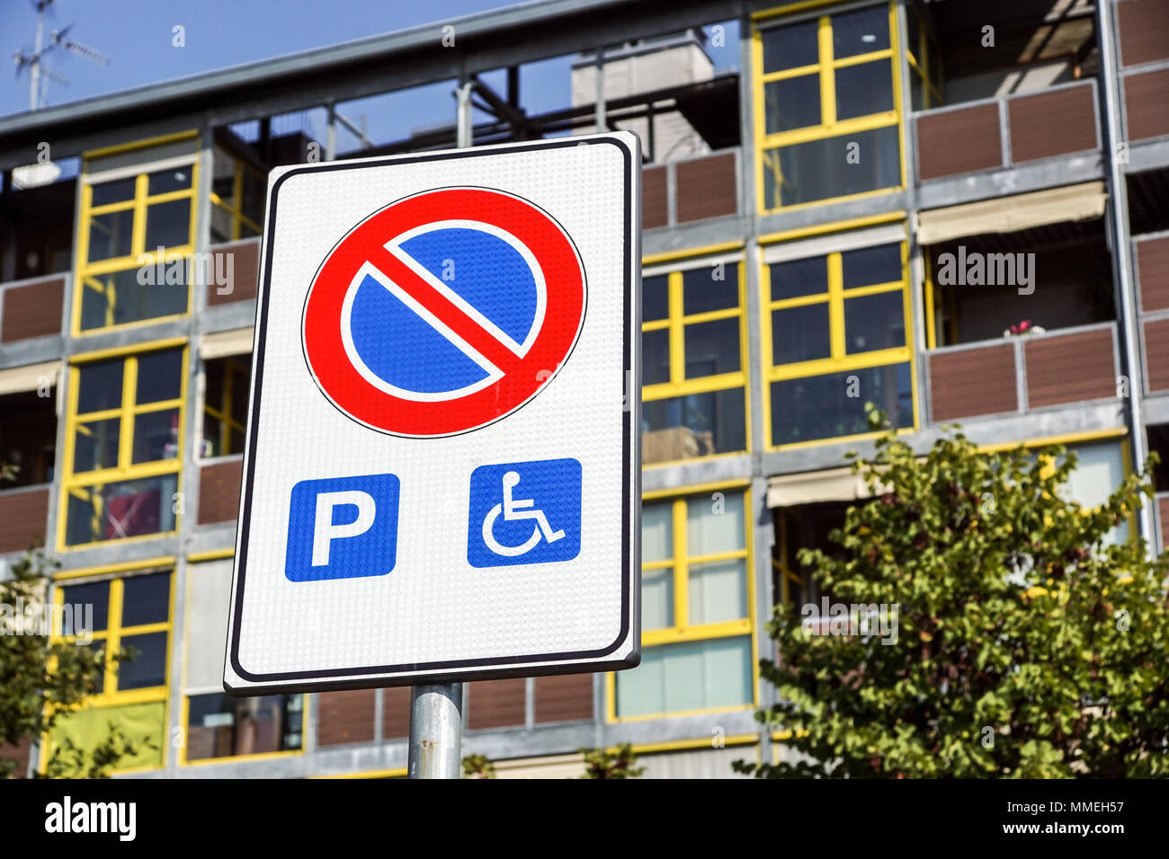 Parcheggio Disabili spazio e modo per sedie a rotelle e segno di simboli su un palo gli automobilisti di avvertimento Foto Stock
