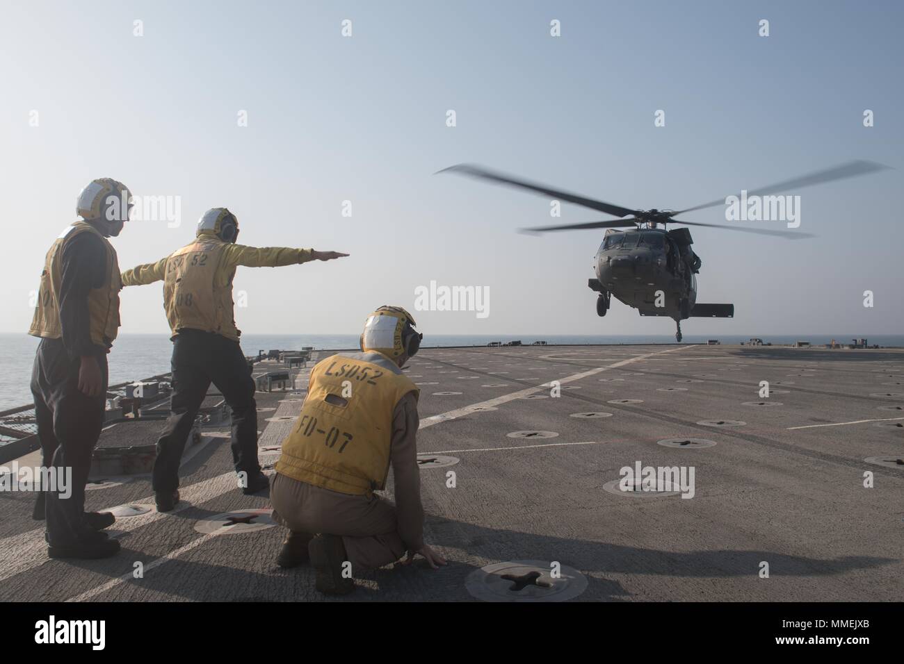 171023-N-OW019-052 U.S 5TH FLOTTA AREA DI OPERAZIONI (ott. 23, 2017) marinaio Miguel Mendez (centro), nativo di Orlando, assegnato alla sezione di coperta a bordo del dock anfibio sbarco nave USS Pearl Harbor (LSD 52), dirige un UH-60 elicottero degli Emirati Arabi Uniti (EAU) Joint Aviation comando durante le operazioni di volo a bordo della nave del ponte di volo a sostegno di ferro Magic 18 come Boatswain compagno del 3° di classe di David Watson e Marine Cpl. Ryan Carr osservare. La magia di ferro 18 è un combinato di bracci-live-fire impegno bilaterale destinato ad ampliare i livelli di cooperazione, migliorare la mutua capacità marittima, Foto Stock