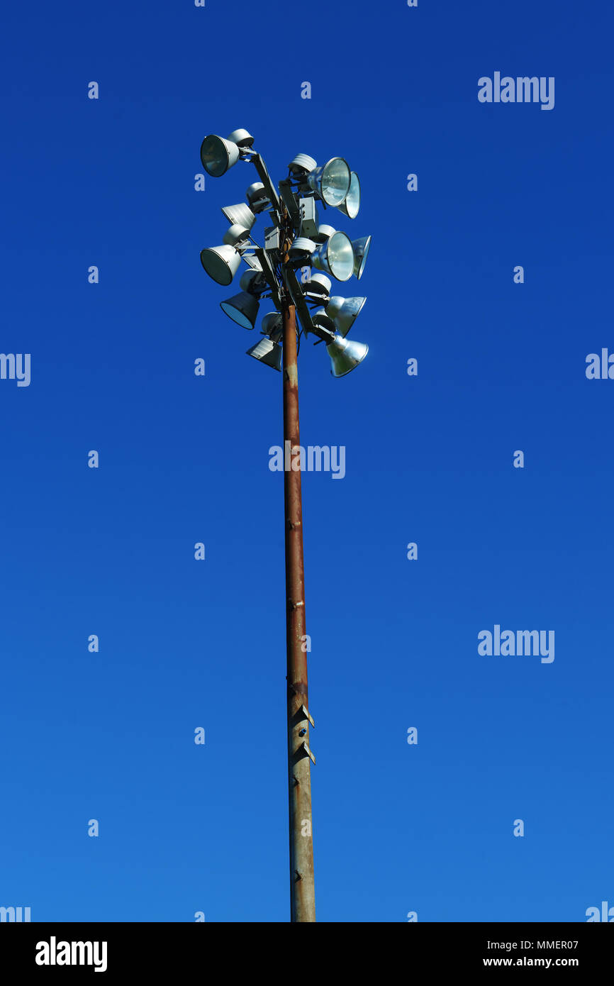 Rusty sport light post in uno stadio contro un profondo cielo blu. Foto Stock
