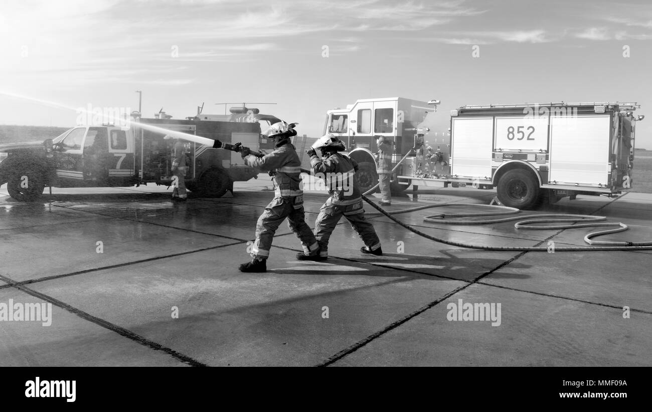 Avieri 1a classe Christopher Rickenbach e Devin Re, 5 Ingegnere Civile Squadron vigili del fuoco, spruzzare un tubo flessibile a Minot Air Force Base, N.D., 20 ott. 2017. La protezione antincendio volo treni regolarmente per assicurare la disponibilità di missione. (U.S. Air Force foto di Airman 1. Classe Alyssa M. Akers) Foto Stock