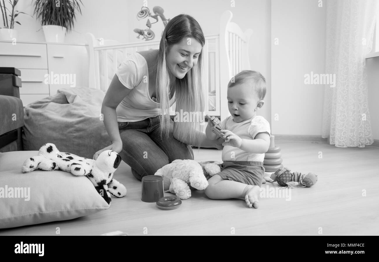 Foto in bianco e nero di adorabili toddler boy giocando sul pavimento con sua madre Foto Stock