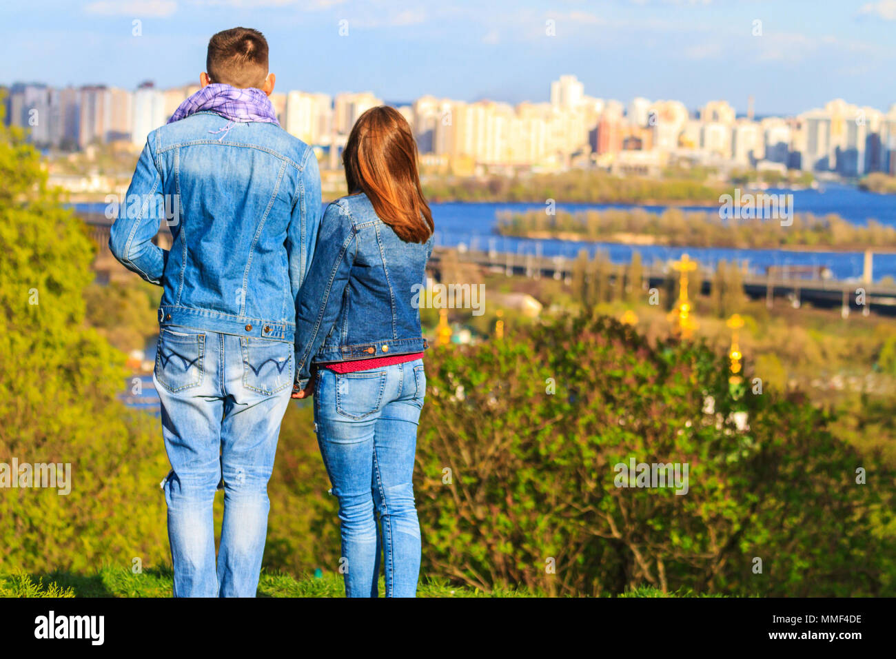 Giovane sorge sul fianco di una collina e guarda il panorama della città Foto Stock
