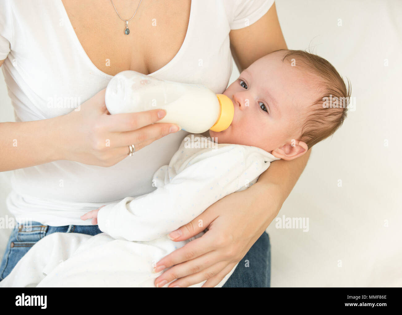 Ritratto di 3 mesi di età bambino bere latte dalla bottiglia sulle madri lap Foto Stock