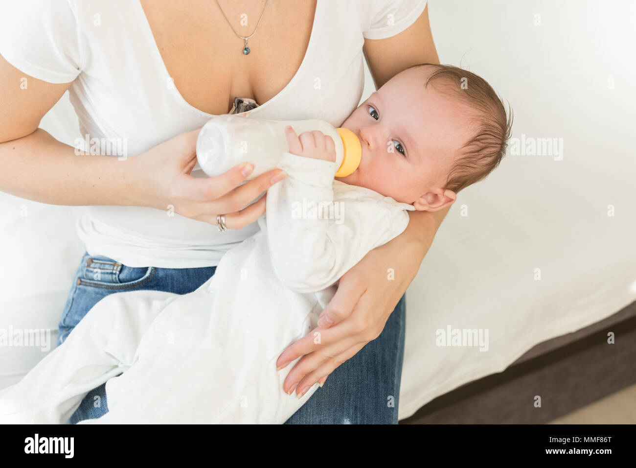 Tonica foto di giovane donna dando una bottiglia di latte per il suo bambino Foto Stock