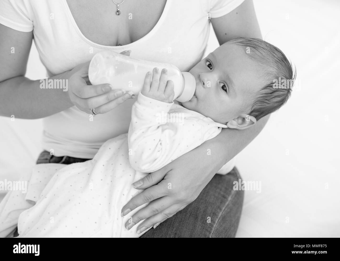 Bianco e nero ritratto di adorabili baby boy bere latte dalla bottiglia Foto Stock