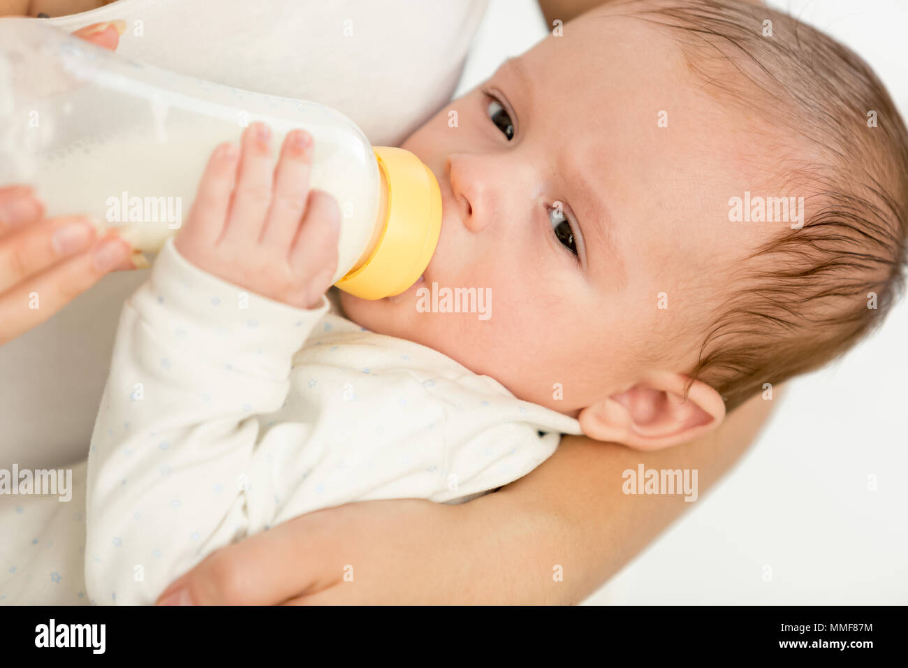 Closeup ritratto di 3 mesi baby boy holdin bottiglia con latte e mangiare Foto Stock