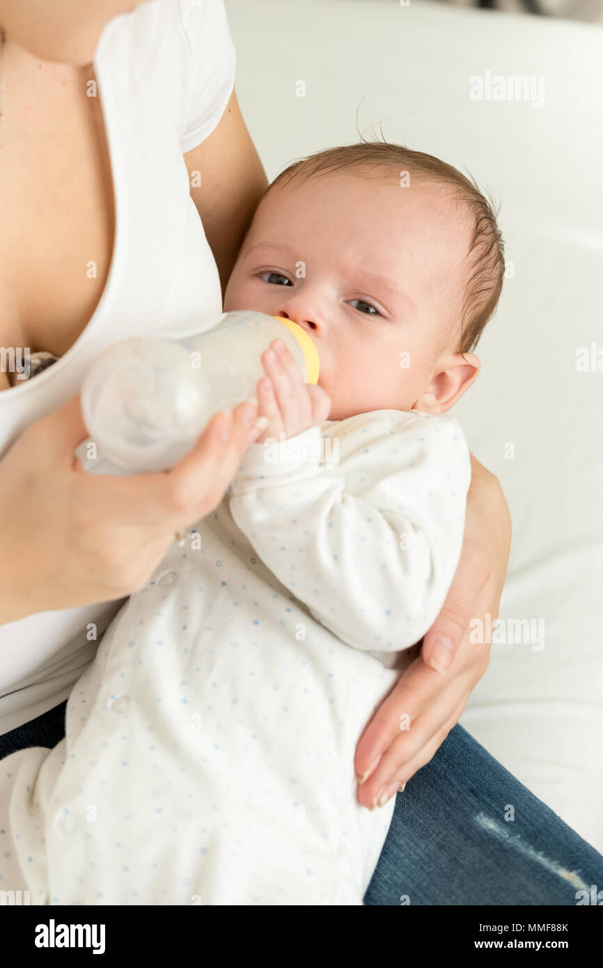 Ritratto di 3 mesi di età bambino giacente sul giro di madri e di mangiare latte dalla bottiglia Foto Stock