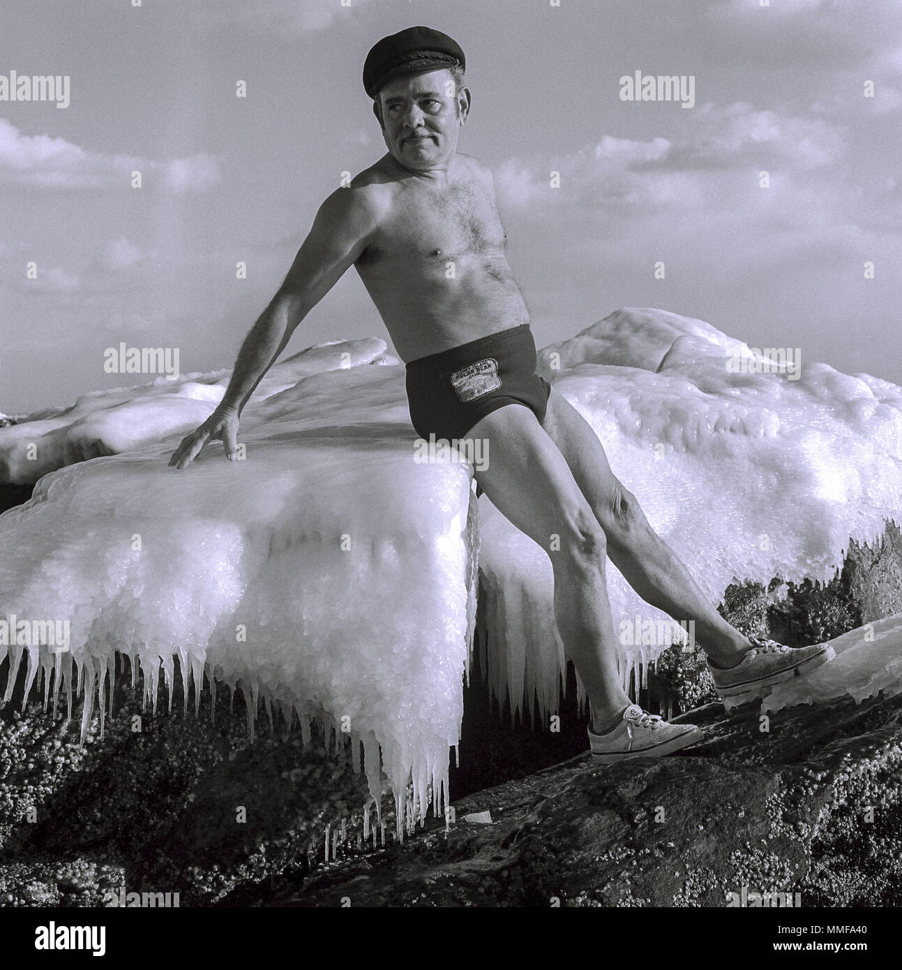 Uomo in costume da bagno seduta sul ghiaccio di Lake George, New York nel  mezzo dell'inverno. Egli è dalla Polar Bear club da Coney Island negli anni  ottanta Foto stock - Alamy