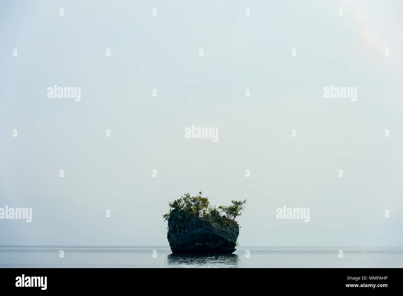 Una piccola isola di calcare in morto un mare calmo. Foto Stock