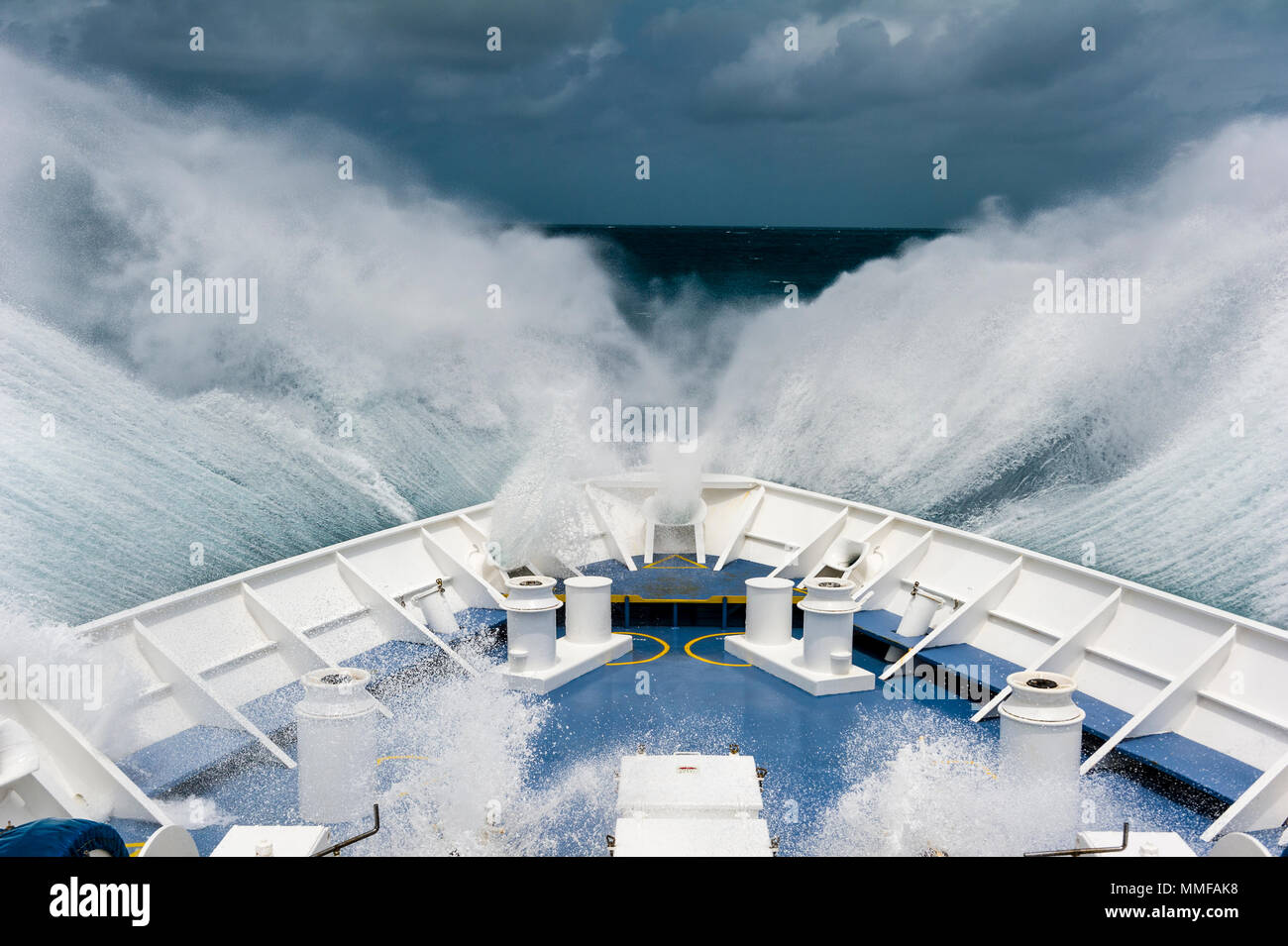 La prua di una nave spedizione aratri attraverso le onde che si infrangono in mare aperto. Foto Stock