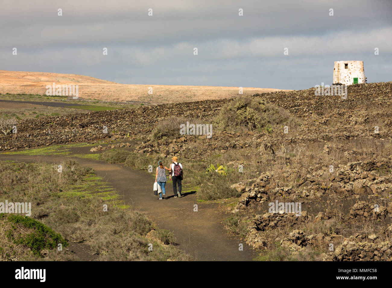 LANZAROTE, Isole canarie, Spagna, Europa: Giovane a piedi attraverso vecchi vigneti abbandonati intorno al cratere Volcan La Corona Foto Stock