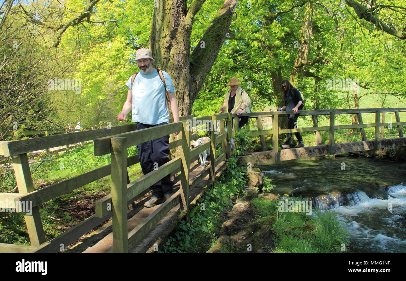Walkers su un ponte sul fiume Colomba a Beresford Dale vicino a Hartington, Peak District, Derbyshire Dales, England Regno Unito a metà primavera Foto Stock