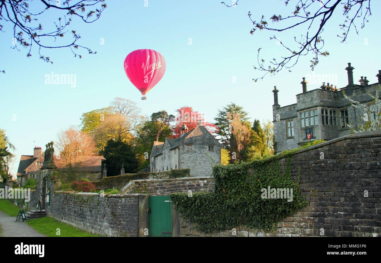 Tissington Hall, Peak District, Derbyshire, Regno Unito. Una mongolfiera vola sopra Tissington Hall nel Parco Nazionale di Peak District, England, Regno Unito Foto Stock