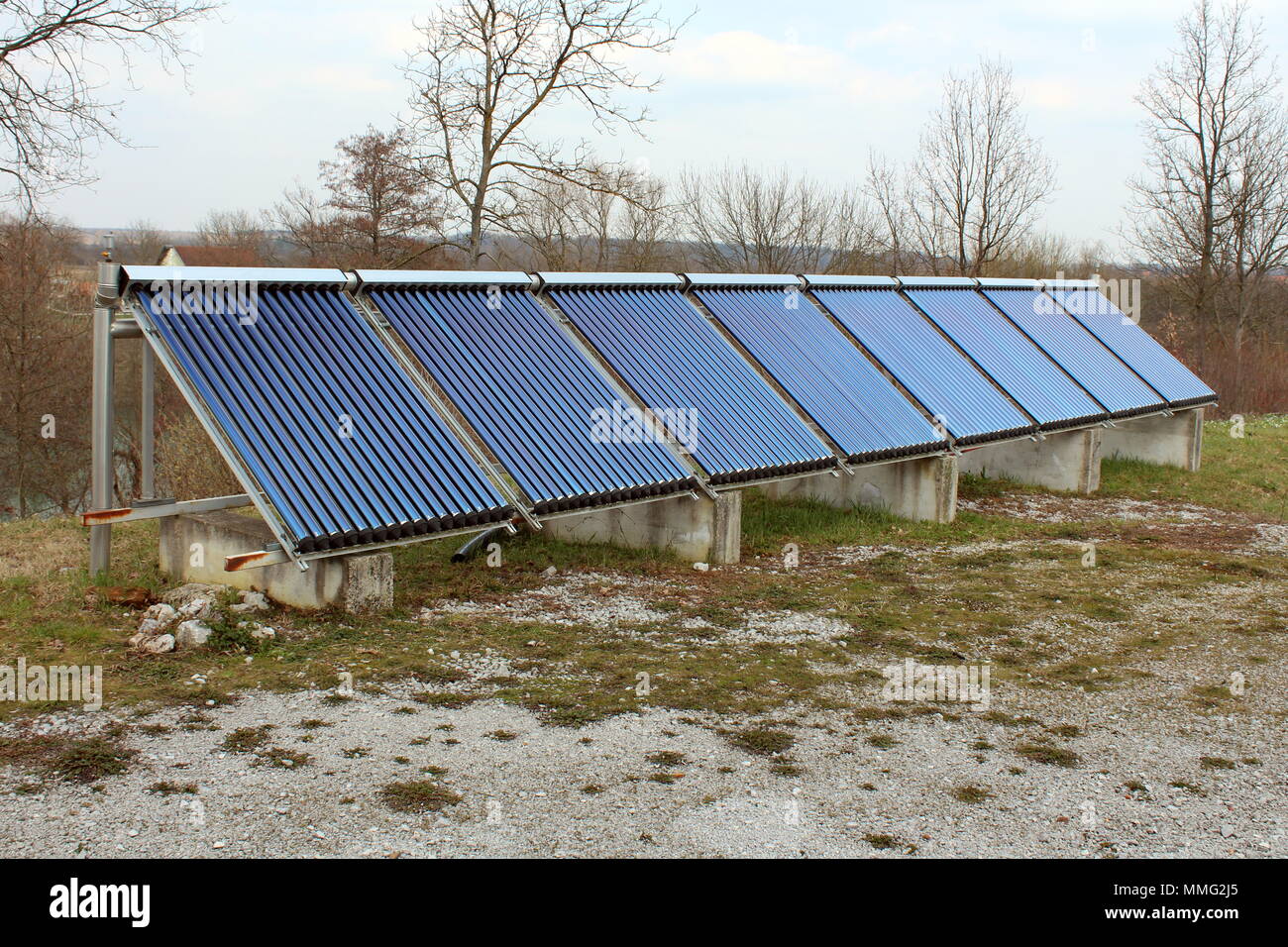 Riscaldamento di Acqua Solare installazione pannelli con otto pannelli montati sulla parte superiore dei tubi metallici e fondamenta in calcestruzzo e circondato con ghiaia, intonso wint Foto Stock