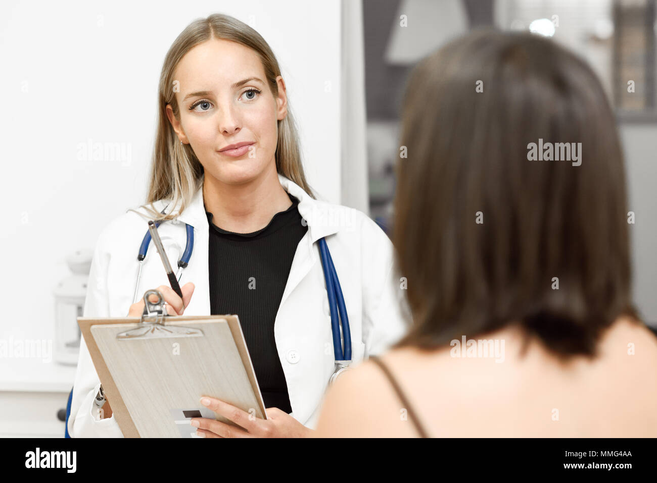Medico donna spiegando la diagnosi per il suo paziente. Brunette donna avente la consultazione con la ragazza bionda in ufficio medico. Foto Stock
