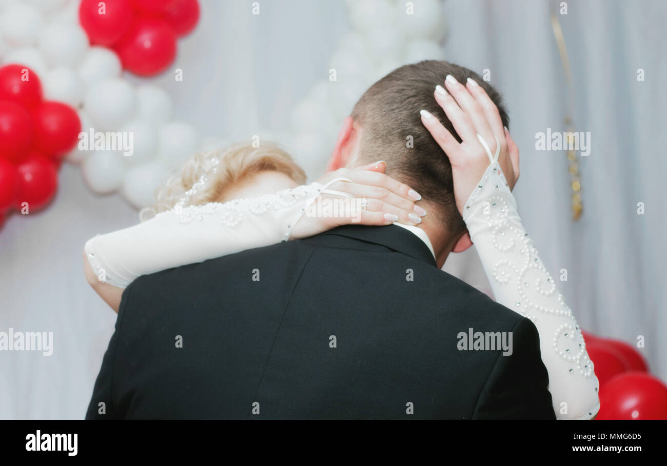 Sposi novelli kissing sullo sfondo di palloncini in piedi torna alla fotocamera. Hugs sposa sposo Foto Stock