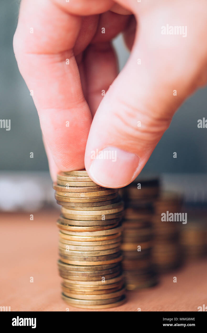 Stretta di mano maschio monete di impilamento. Risparmio di denaro e di concetto di budget. Foto Stock