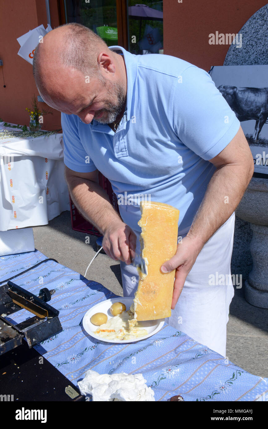 Mugena, Svizzera - 7 Maggio 2018: uomo preparare una porzione di raclette in Mugena sulle alpi svizzere Foto Stock