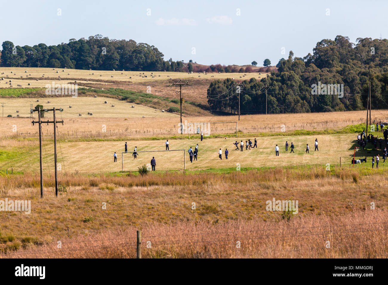 Scuola calcio soccer i bambini giocando pomeriggio di gioco in un allevamento paesaggio panoramico. Foto Stock