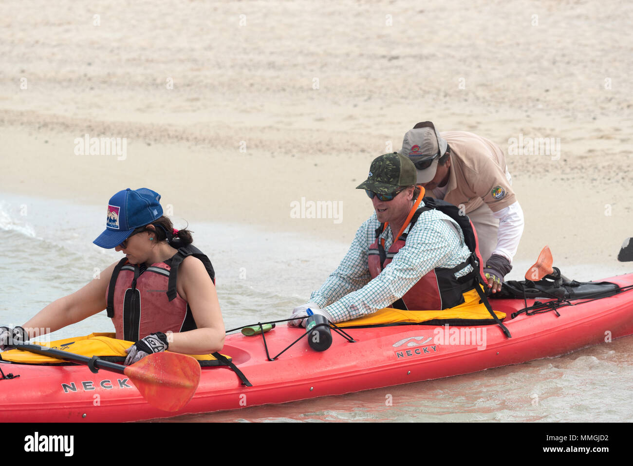 Guida ecuadoriana aiutando paddler fissare il mantello a spruzzo su un kayak di mare viaggio nelle isole Galapagos, Ecuador. Foto Stock