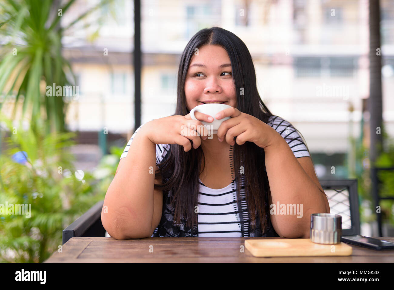 Bellissimo il sovrappeso donna asiatica di relax presso la caffetteria Foto Stock