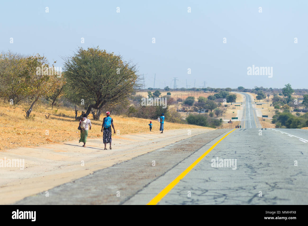 Povera gente che camminava sul ciglio della strada nelle zone rurali Caprivi Strip, la più popolosa regione in Namibia, Africa. Foto Stock