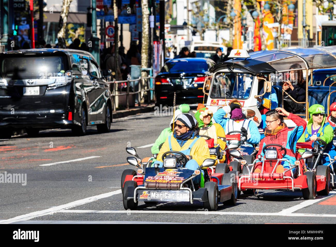 Tokyo, Shibuya crossing. Popolari attività turistiche, guida MariCars, Mario Kart mentre vestita come Mario caratteri. Fila di attesa in attraversamento. Foto Stock