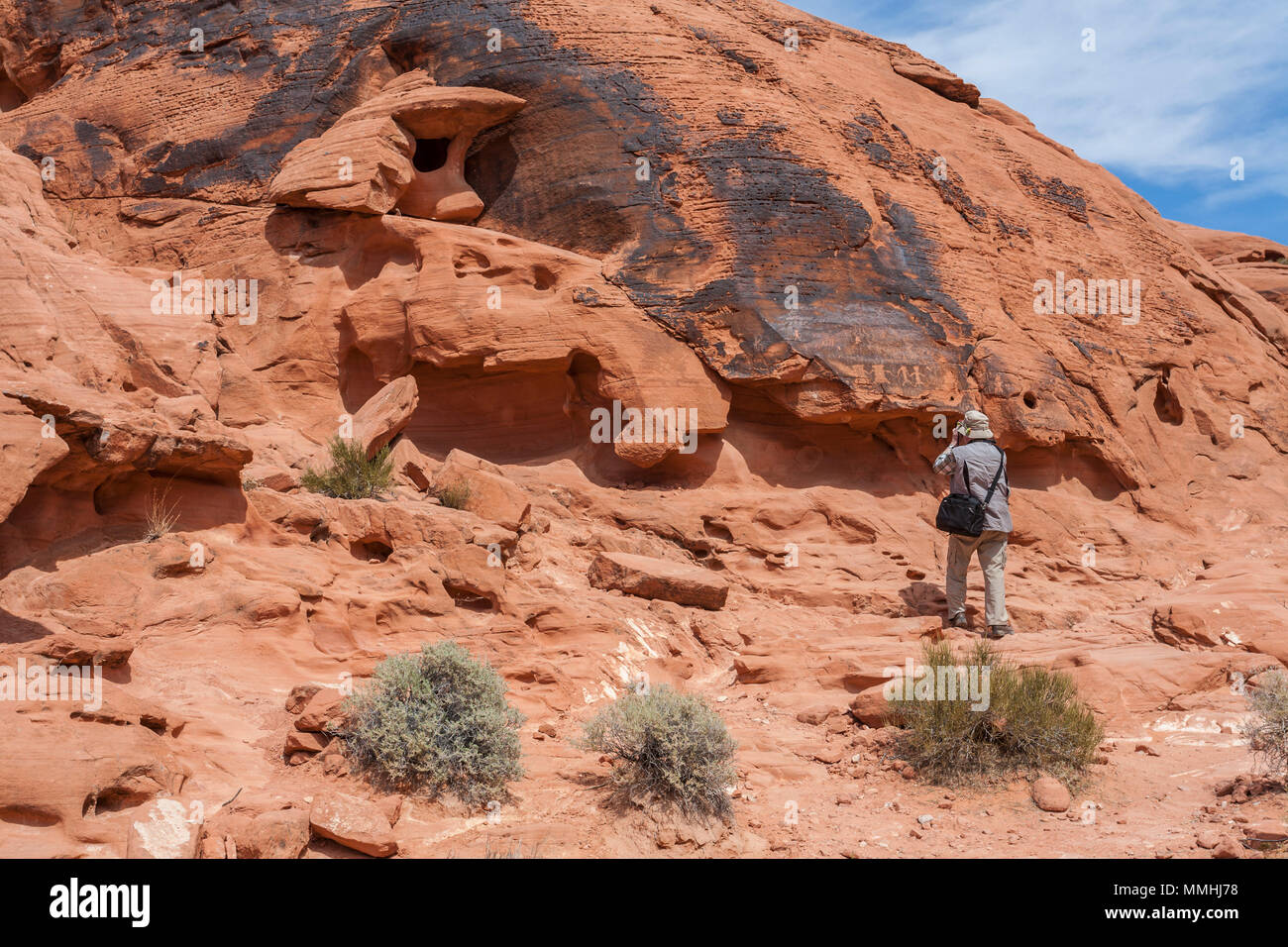 Visitatore di fotografare i simboli incisi in rosso Aztec roccia arenaria formazioni in il Parco della Valle di Fire State in Overton, Nevada a nord-est di Las Vegas Foto Stock