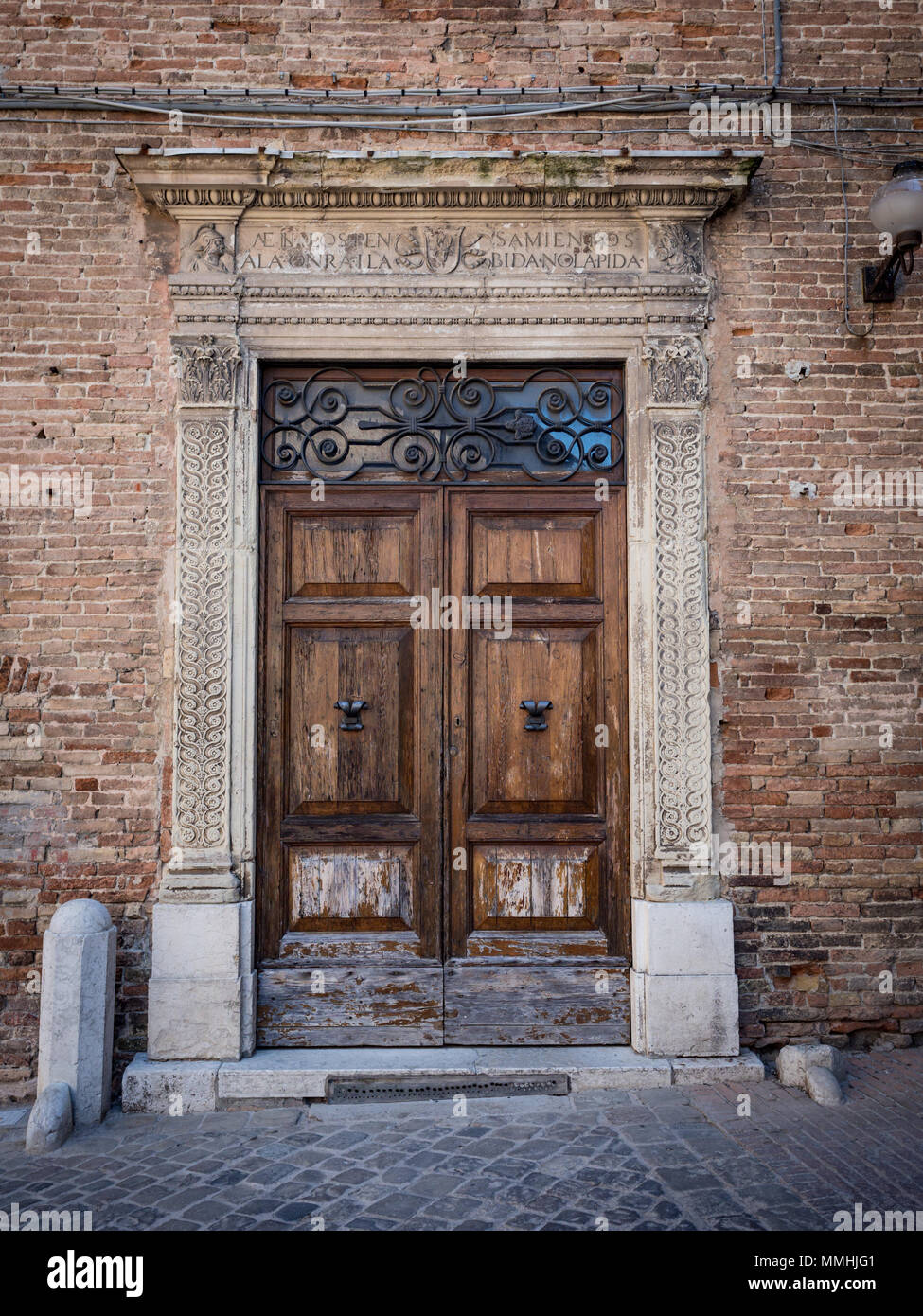 Il vecchio portale in legno con colonne e architrave in pietra bianca intagliate con motivi floreali. Foto Stock