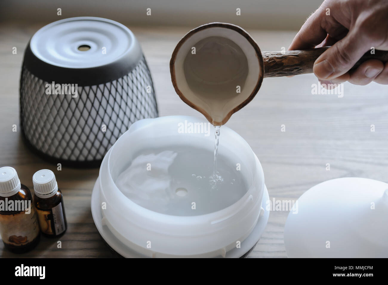 Un uomo è versare acqua in un diffusore di aroma. Foto Stock