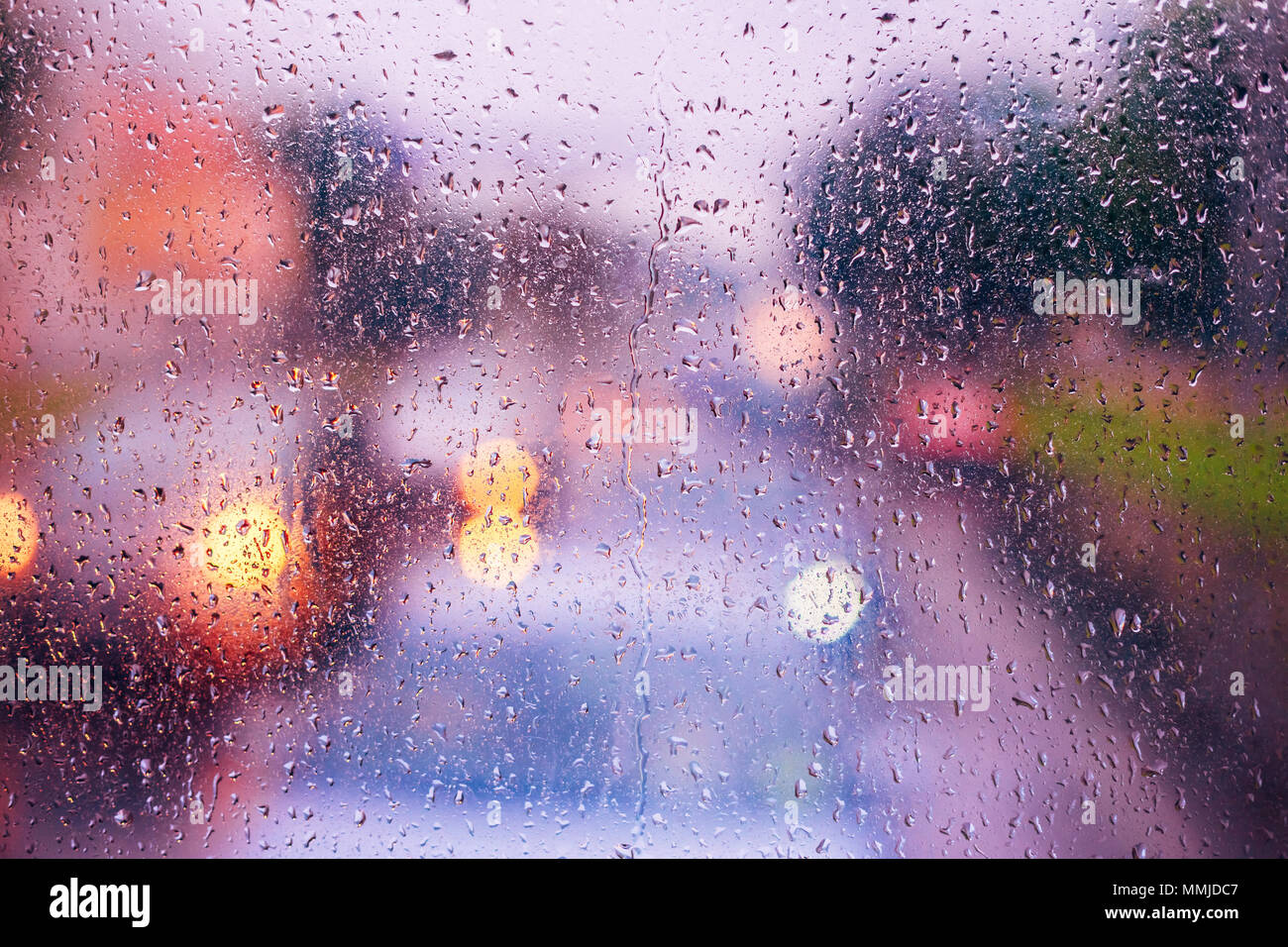 Gocce di pioggia sul vetro azzurro sfondo. Street Bokeh Lights Out di messa a fuoco. Autunno sfondo astratto Foto Stock