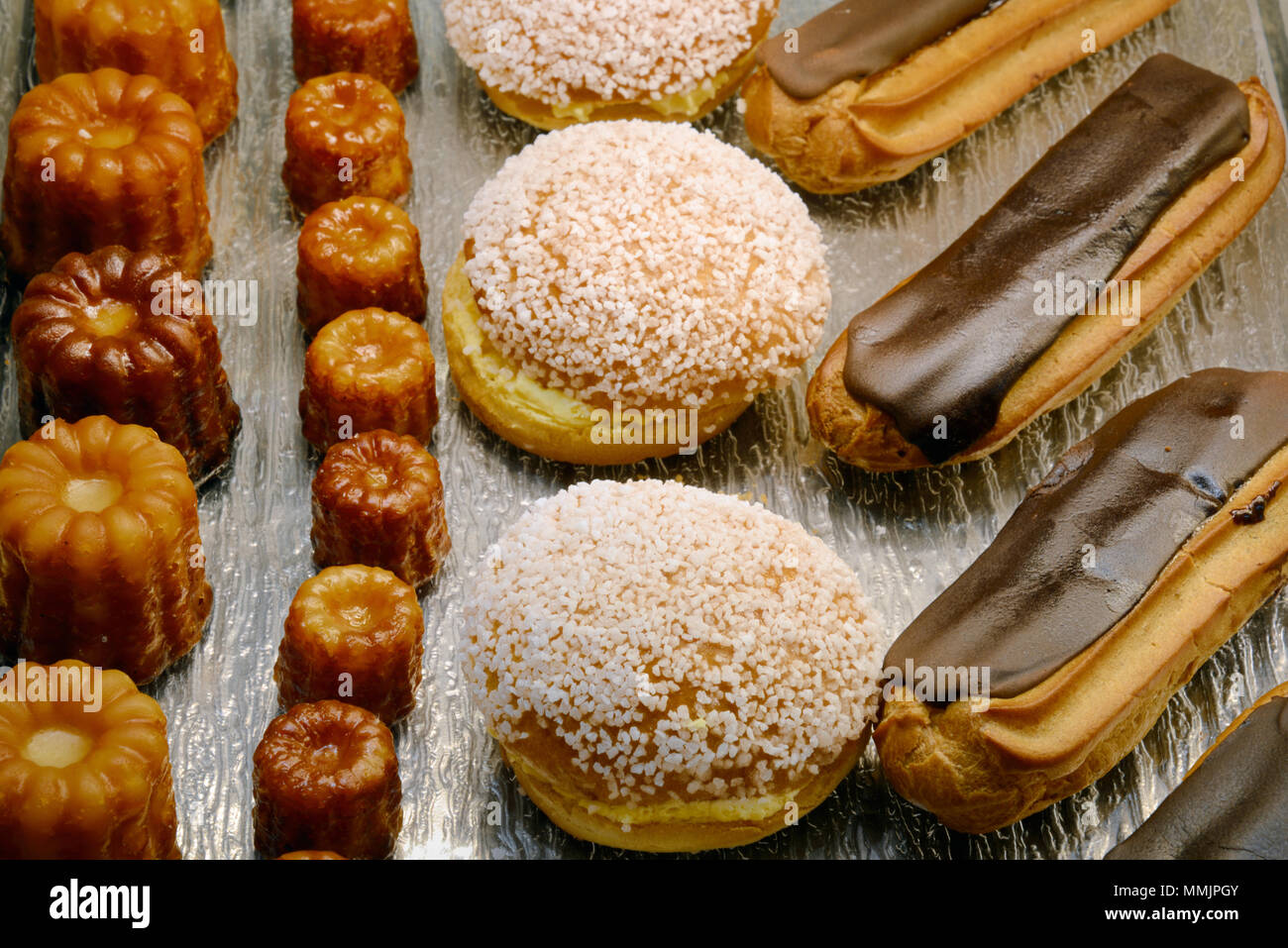 Visualizzazione di Canelés, Tropezienne torte di panna e cioccolato Eclairs torte e pasticcini in una pasticceria francese in Francia Foto Stock