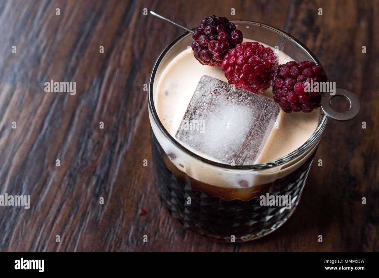 Nero / birra scura cocktail con more e ghiaccio sulla superficie di legno. Concetto di bevanda. Foto Stock