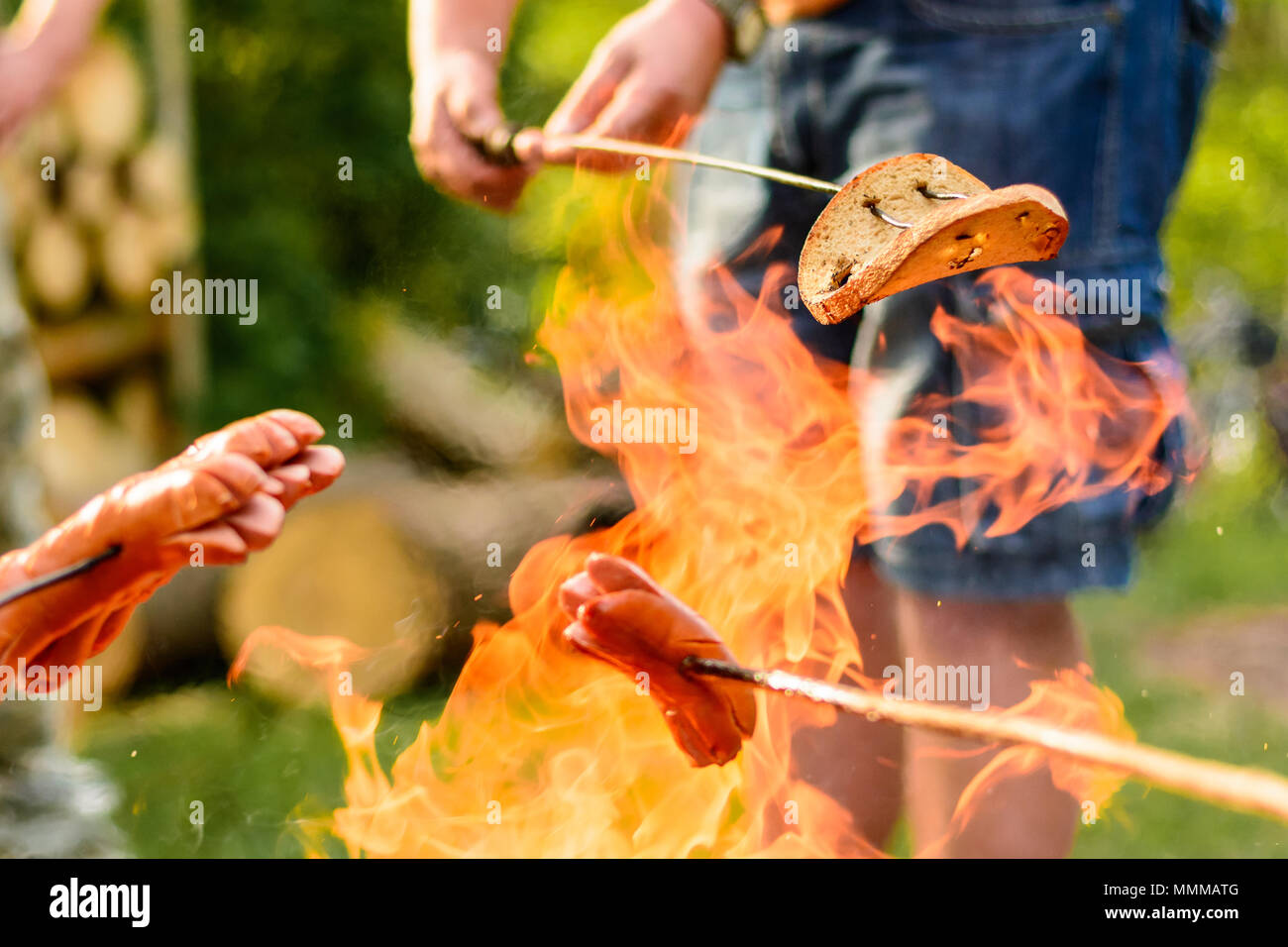 Grigliare salsicce oltre a un falò nella foresta. Vacanza e il campeggio estivo in campagna. Beltaine notte nella Repubblica Ceca. Giorno di maggio celebrat Foto Stock