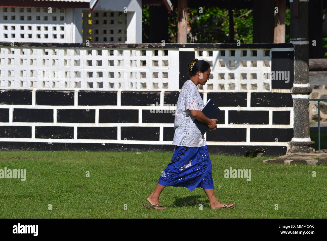 Signora Wallisian cammina davanti a un edificio governativo, Mata-Utu, isola di Wallis, Wallis & Futuna, Sud Pacifico Foto Stock