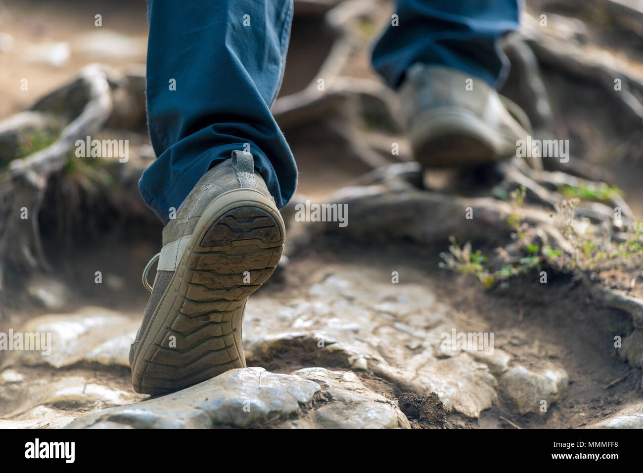 Il turista si inerpica su per la montagna, le sue gambe di close-up sulle pietre Foto Stock