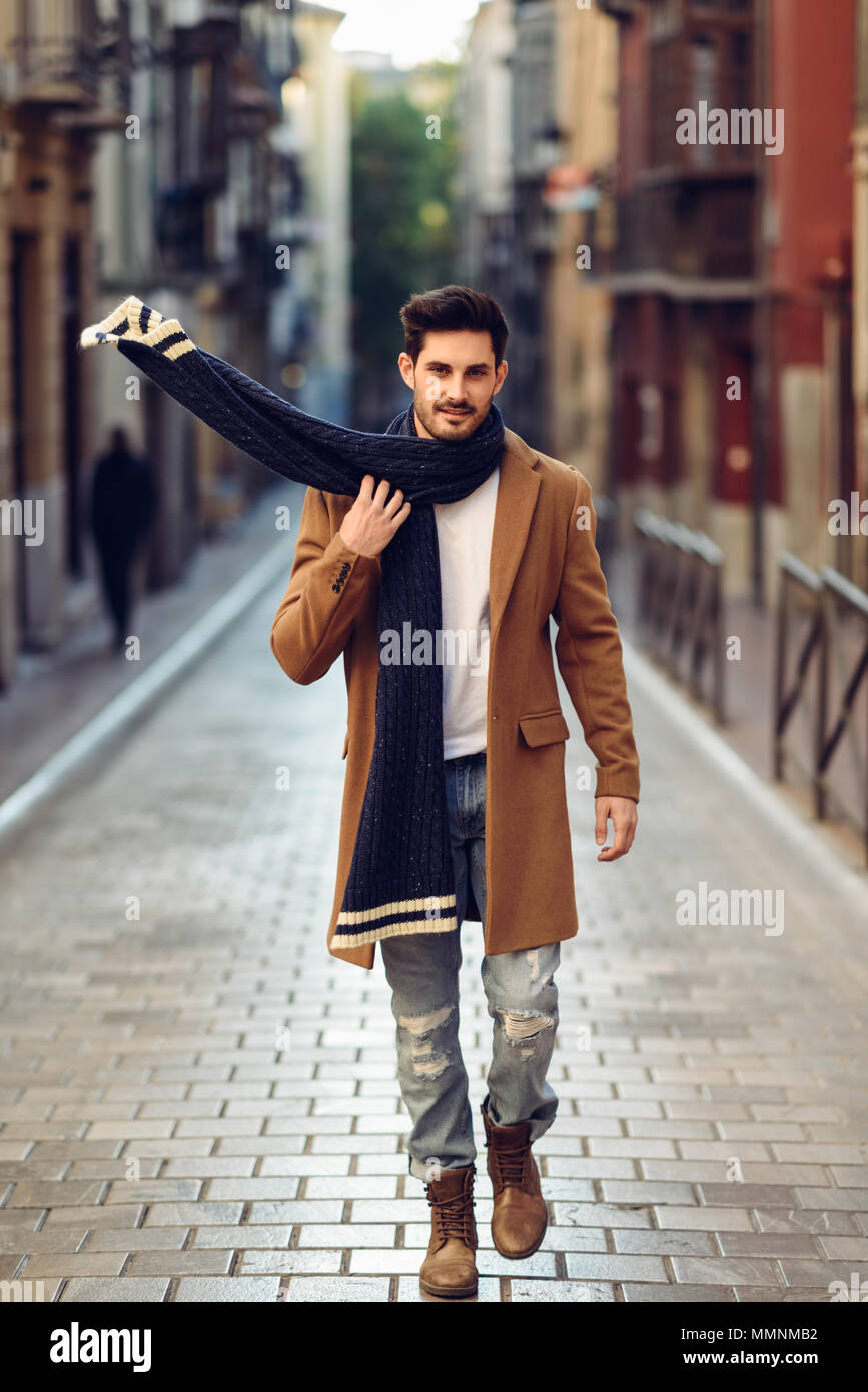 Giovane uomo che indossa abbigliamento invernale in strada. Giovane ragazzo  barbuto con moderni acconciatura con rivestimento, sciarpa, blue jeans e  maglietta Foto stock - Alamy