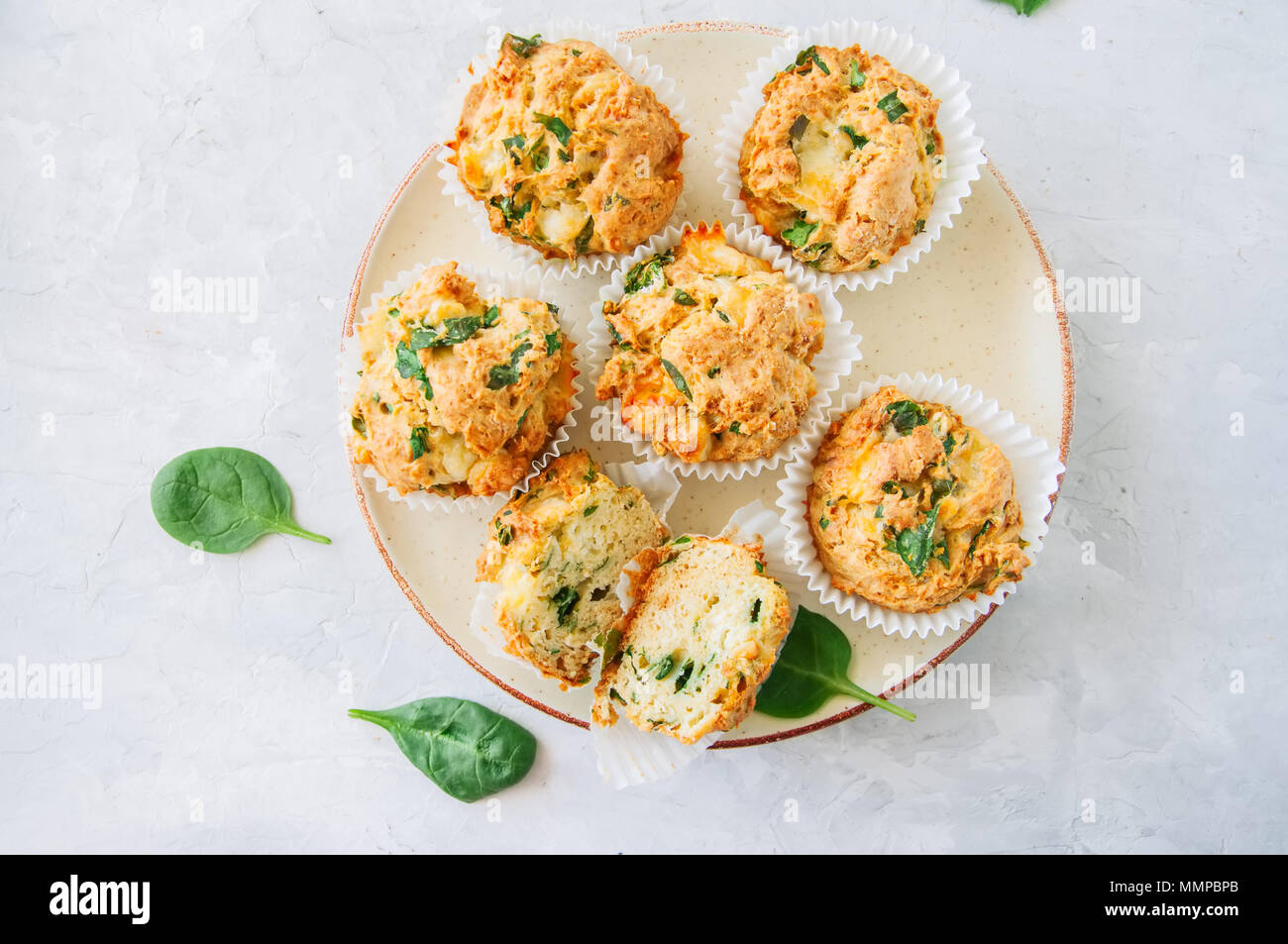 Salato spinaci patate e formaggio feta muffin servita su una piastra. Pietra Bianca dello sfondo. Vista dall'alto. Foto Stock